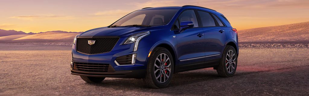 Blue compact luxury SUV parked on a desert landscape at sunset, featuring a bold grille, LED headlights, and alloy wheels.